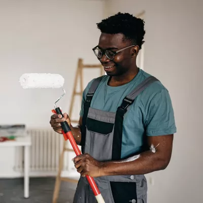 A young man holds a paint roller.