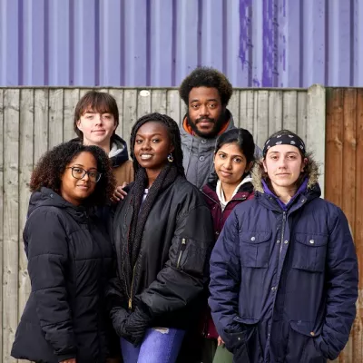 A group of young people stand together outside looking hopeful