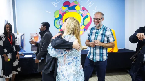 Two people embrace with happy onlookers standing in the background.