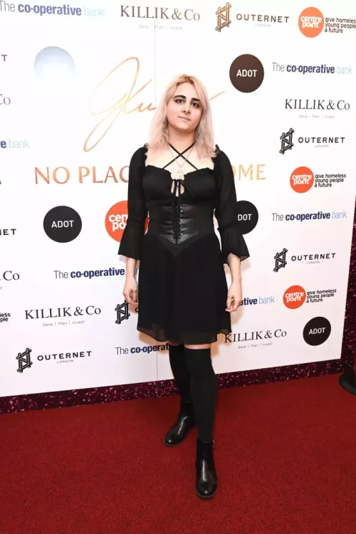 Young person in black dress standing in front of sponsor board