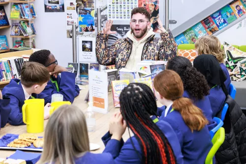 Dean McCullough sits with pupils at Manchester Enterprise Academy