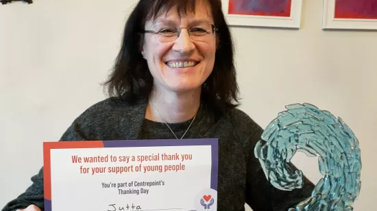 Jutta smiles and holds her Thanking Day certificate