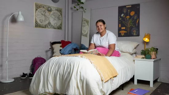 Mia smiling on her bed in a Centrepoint service whilst reading