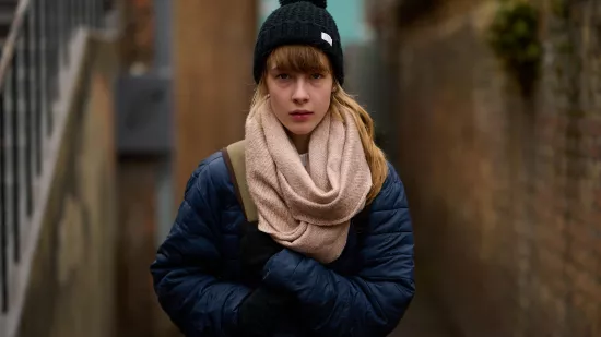 Young woman alone in alleyway, looking nervous.