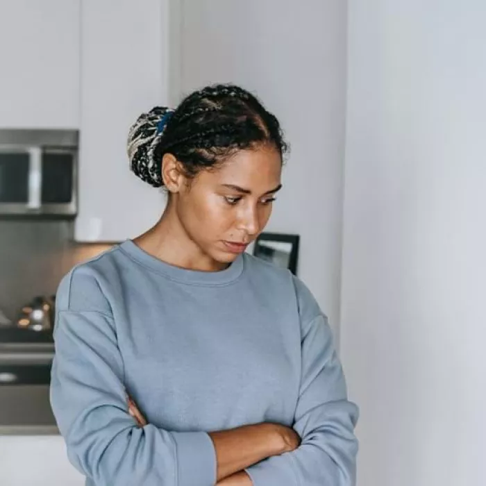 Young person in kitchen holding stomach