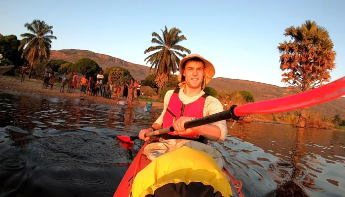 Photograph of Ben Harris, fundraiser, in a kayak on a lake. Ben is wearing a hat and trees can be seen in the background