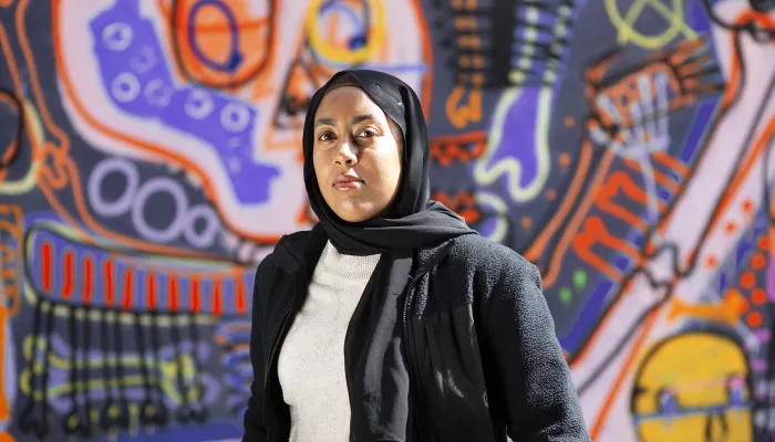 Young person standing in front of graffiti wall