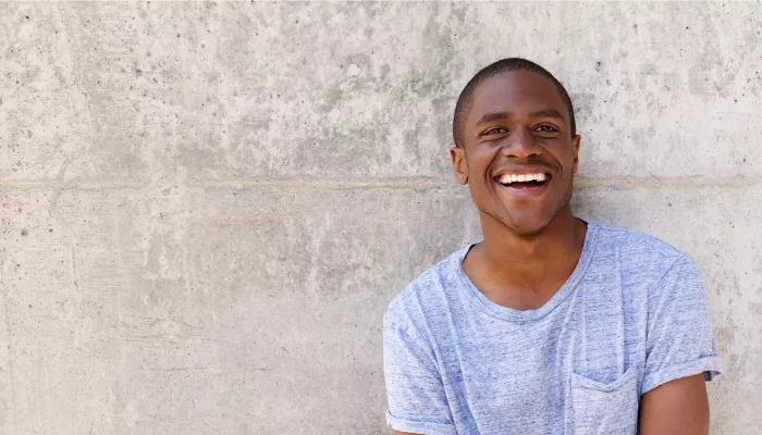 Young person in a light blue t-shirt against a grey wall