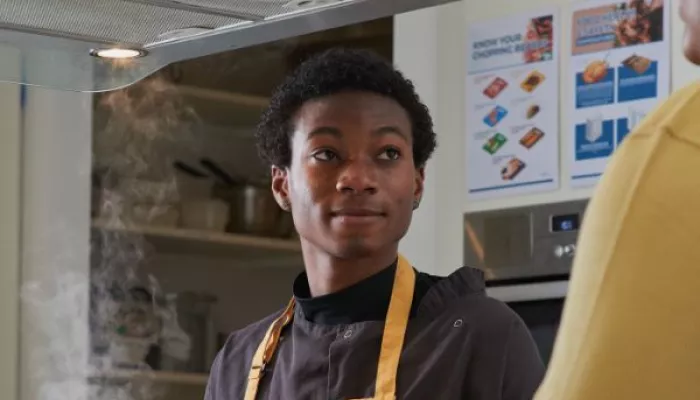 Young person wearing an apron and preparing food