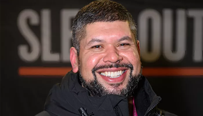 Man smiling in front of Sleep Out signage