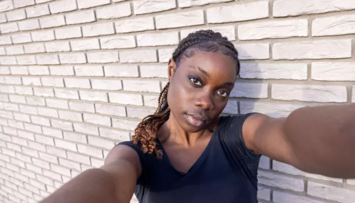 young person taking selfie against brick wall