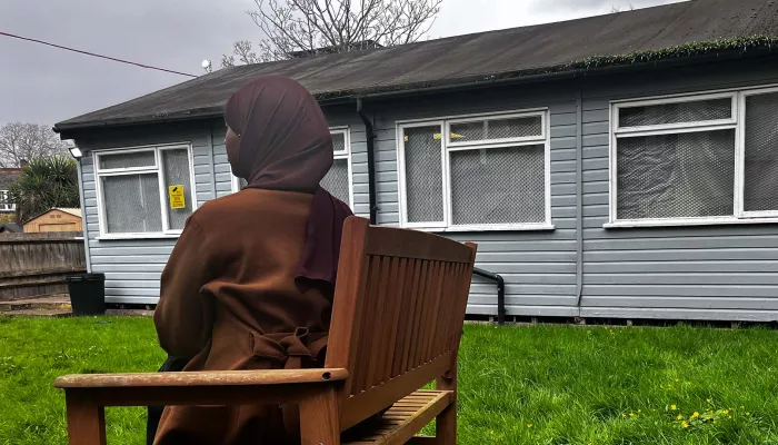 Young person in headscarf in side profile by a scout hut