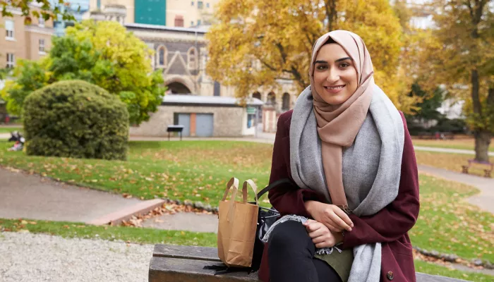 Young person sitting outside wearing a head scarf