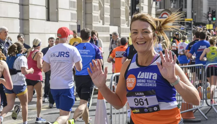 Woman runs and smiles at the camera wearing a Centrepoint branded running vest