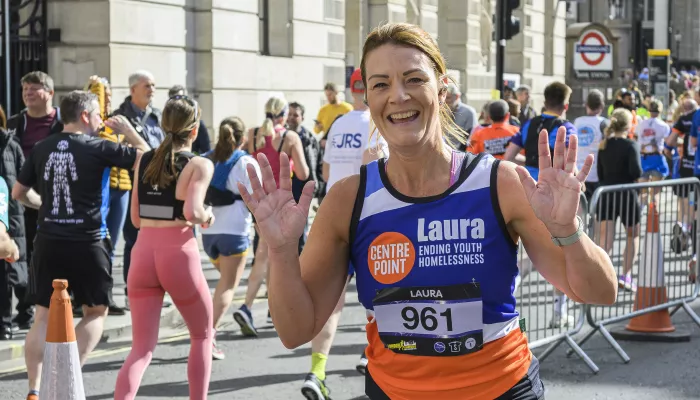 Runner waving in a Centrepoint vest at a marathon