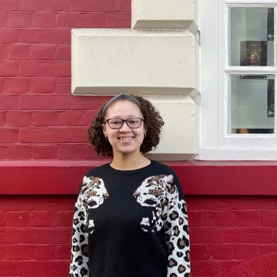 Young person standing in front of a red wall and window