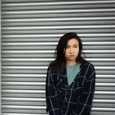 Homeless young person standing against a metal shutter.