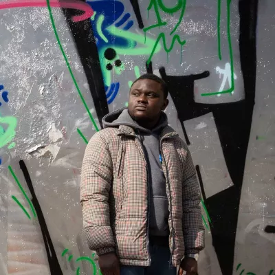 Young person standing against a wall of graffiti 