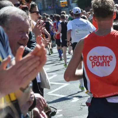 Person running at an organised running event surrounded by clapping onlookers.