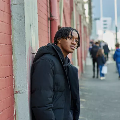 Picture of a young person outside leaning against a wall