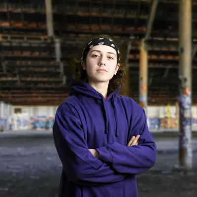 Young person in blue hoodie with arms crossed