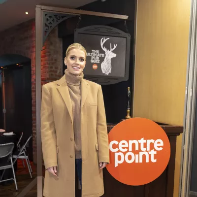 Lady Kitty Spencer smiles and stands in front of the Centrepoint logo in a pub.