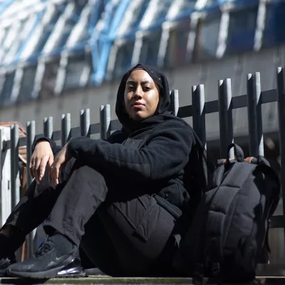 Young person sitting outside with backpack